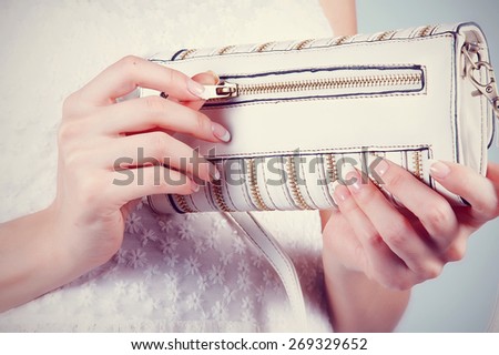 Beautiful female hands with manicure hold an open small white handbag
