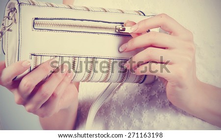 Beautiful female hands with manicure hold an open white handbag