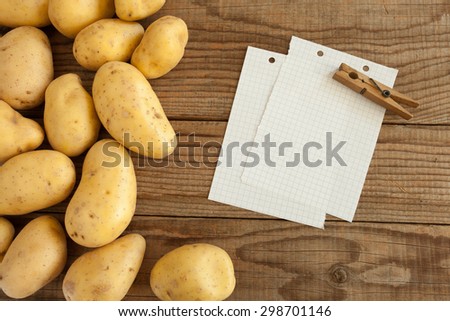 block note on wooden table next to fresh potatoes