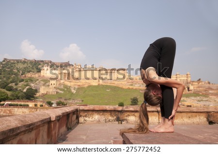 Yoga pose Standing forward fold or Uttanasana  at Amber fort, Jaipur, India