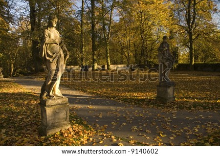 Two statues of greek goddesses in the park during autumn.