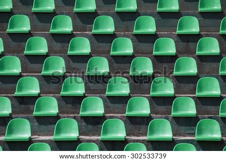 green plastic stadium seats in rows. The seats are filled the frame as background. This is a day shot of an empty stadium.