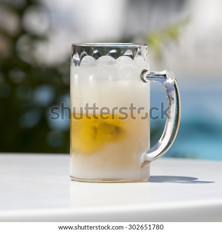 Extremely cold glass with beer on a table in a very hot summer day. Image with clipping path.