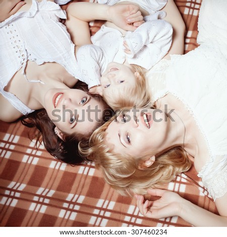 Three generations: grandma, mom and daughter - happy and smiling, lying on the blanket