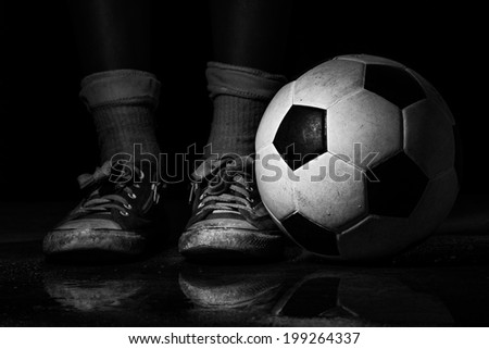 Black and white dirty sneakers with soccer ball on black background