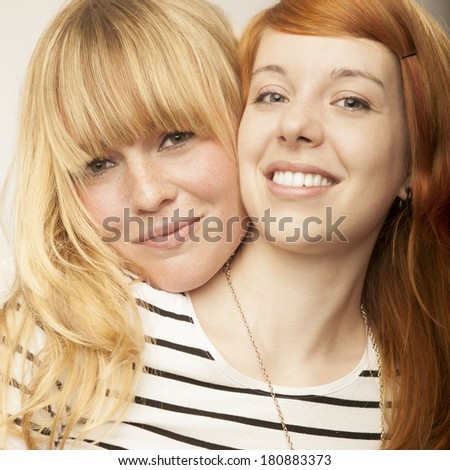 red and blond haired girls friends laughing and hug