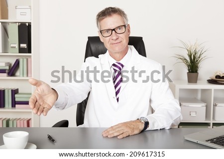 very welcoming family doctor showing take a seat please hand sign, looking at camera