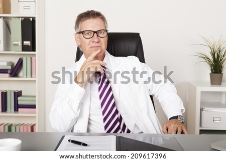 Serious Middle Age Medical Specialist Sitting Down While Looking at Camera