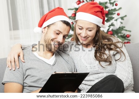 happy young couple think about to do list for christmas eve on sofa