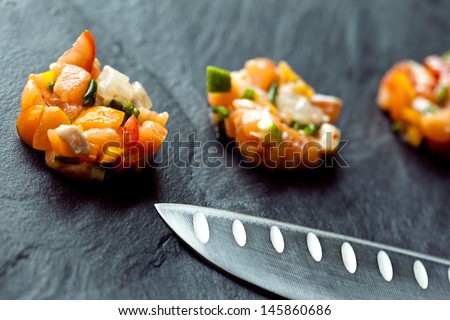 Fish tartare and japanese knife on a slate table