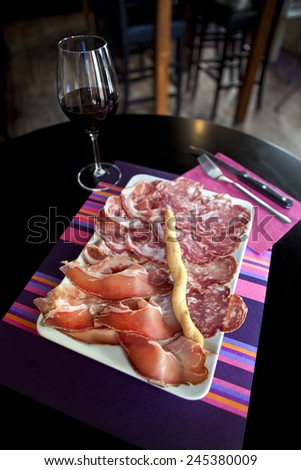 Ham, sausage and glass of red wine on the table of a bistro