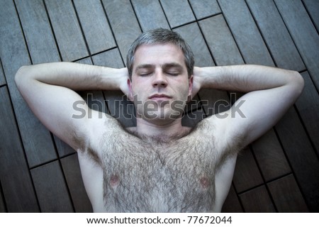 Young hairy man relaxing on a wooden terrace