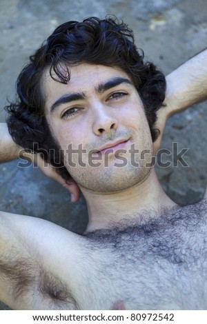 Young and hairy shirtless man leaning against a wall