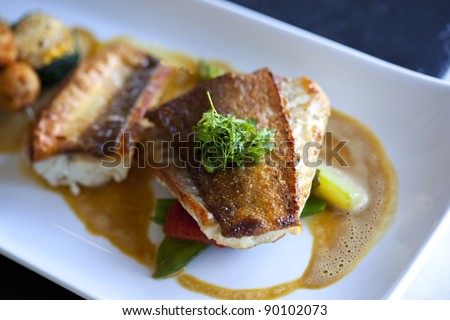 Gourmet dish with fish, vegetables, and seafood sauce