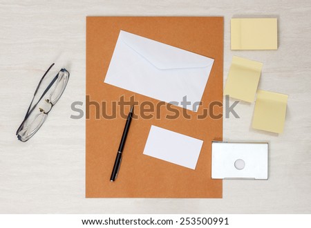 A set of blank envelopes with paper, pen, glasses, business card ans sticky notes