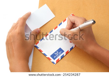Female hand writing address on envelope holding a business card