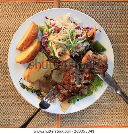 Natural light photo of Cambodian barracuda steak with french fries and salad on mats with tableware top view 2