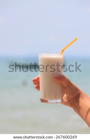 Female hand holding milk shake with tropical sea view background view 4
