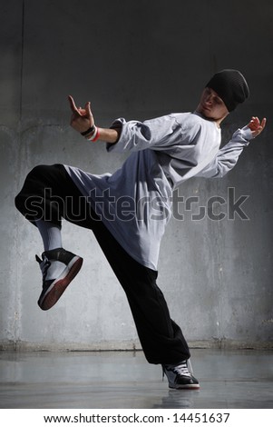 cool looking hip-hop dancer posing on old wall