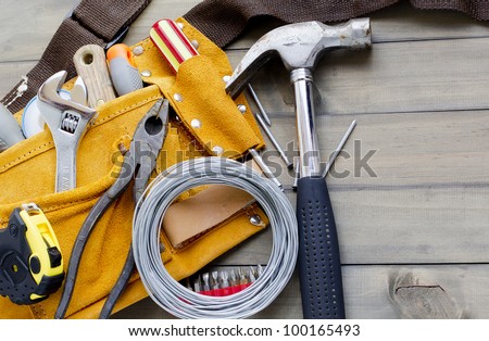 home renovation in progress. tool belt with various tools against wooden surface, add your text.