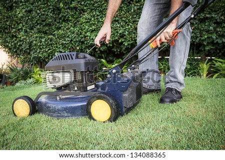 A low angle view of a man preparing for lawn mowing