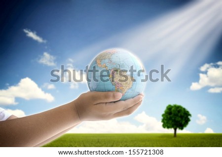 A conceptual image of a boy holding the earth globe with his two hand. A symbol of hope, future generation and  saving environment legacy for future generation.