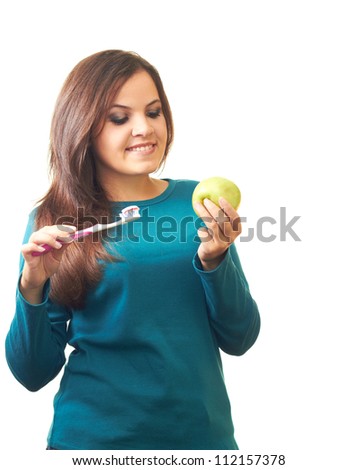 Attractive smiling girl in a blue shirt holding in her right hand and a toothbrush in her left hand holding an apple and looking at him. Isolated on white background