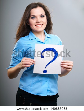 Attractive young woman in a blue shirt. Woman holds a poster with a big question mark. Isolated on gray background