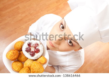 Woman chef cook in uniform holding tray of cookies.
