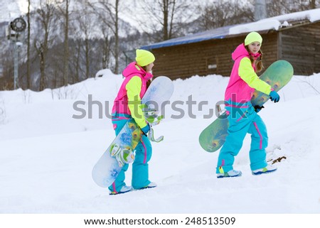 SOCHI, RUSSIA - FEBRUARY 26, 2014: Two girls go with snowboards in hand at the ski resort.