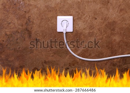 grunge wall with an electrical outlet and fire. Danger