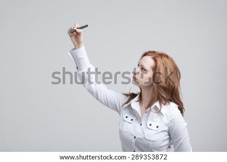 young woman with pen  writes or shows on grey background