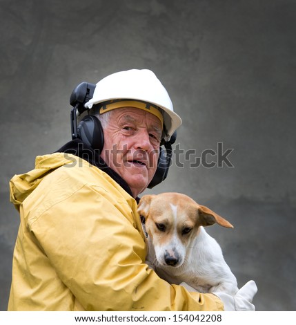 Old man in safety suit holds dog in his arms