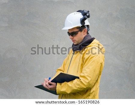 Engineer in safety suit writing a note in building log