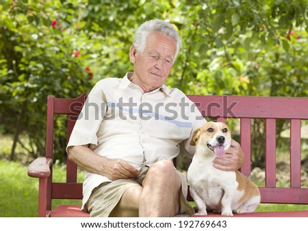 Old man cuddling his dog on bench in garden