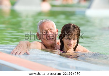 Grandfather with granddaughter enjoying in the swimming pool