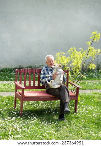 Old man playing with his dog on bench in garden