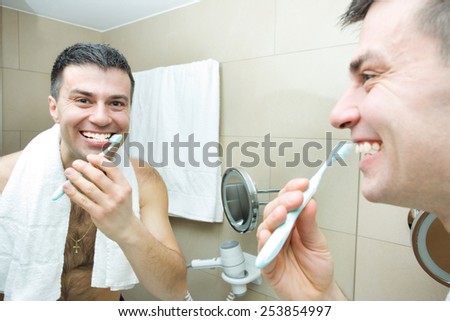 Reflection of man brushing teeth in bathroom mirror