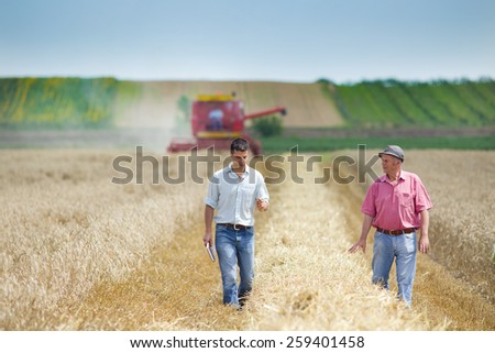 Peasant and business man talking on wheat field during harvesting
