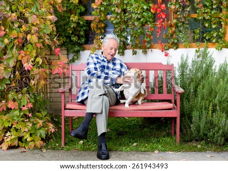 Senior man playing with his dog on the bench in courtyard