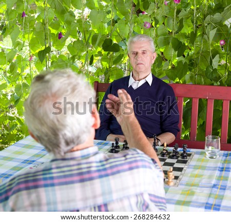 Two senior men talking in courtyard before chess match