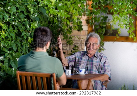 Serious old man talking with grandson and explaining using hand