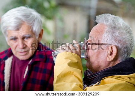 Two senior men sitting on bench in the park and talking