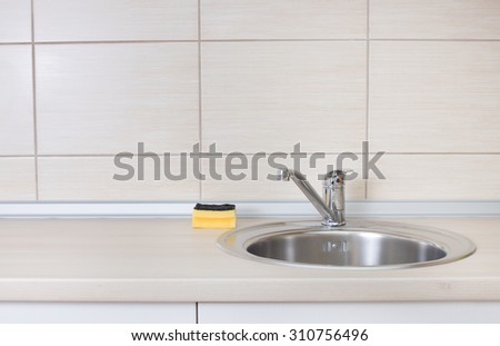 Close up of kitchen countertop with sink and sponge for dish cleaning