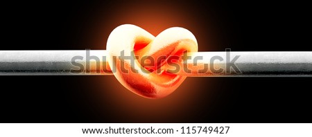 A metal pole twisted into a knotted shape that resembles a heart thats glowing red hot on an isolated background