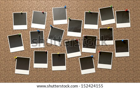A front view of a collection of many blank instant photograph films pinned to a cork bulletin board with various colored pushpins