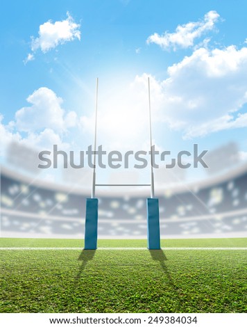 A rugby stadium with rugby posts on a marked green grass pitch in the daytime under a blue sky