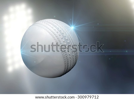 A regular white cricket ball flying through the air on an a outdoor stadium background during the night