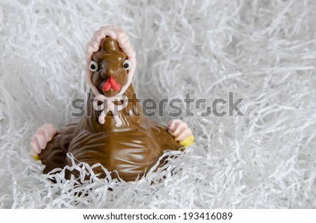 Chocolate Easter hen on a white paper nest