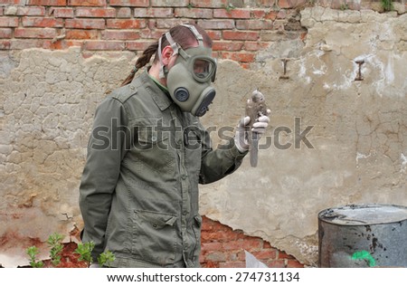 Man with gas mask and green military  clothes  explores  dead bird after chemical disaster.